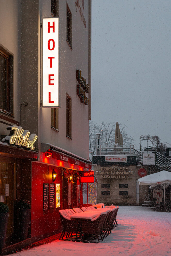 Mit Schnee bedeckte Tische und Stühle, bei Nacht, in der Kölner Altstadt