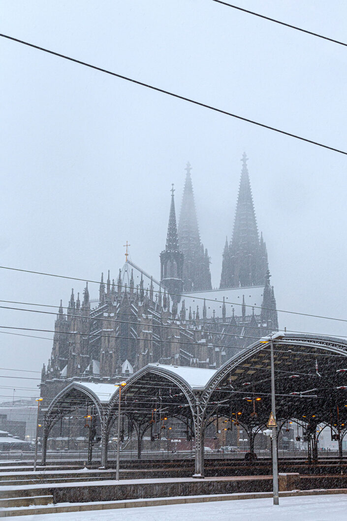 Ansicht der Metallkonstruktion über den Gleisen des Hauptbahnhof, im Hintergrund die Domspitzen im Nebel