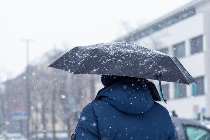Fußgänger, der sich mit einem Schirm vor Schnee schützt