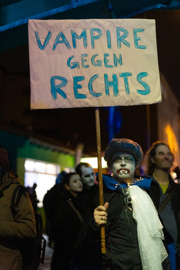 Ein als Vampire verkleideter Teilnehmer, der ein Plakat mit der Aufschrift "Vampire gegen Rechts" hält